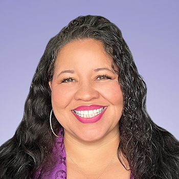 Headshot of a smiling woman with long, wavy black hair in front of a light purple background.