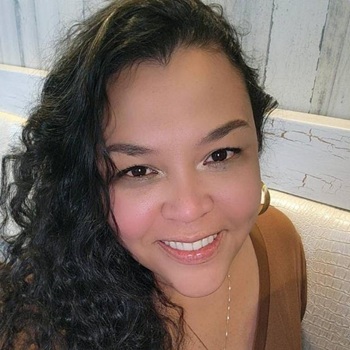 Photo of a woman smiling with long curly black hair.