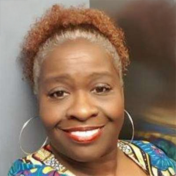 Headshot of a smiling woman with hoop earrings and her hair tied up.