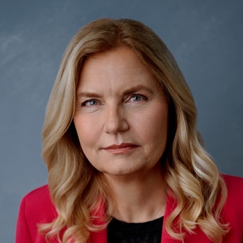 Headshot of a woman with a red blazer in a portrait studio.