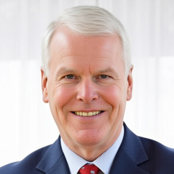 Headshot of a smiling man with white hair in a blue suit and red-patterned tie.