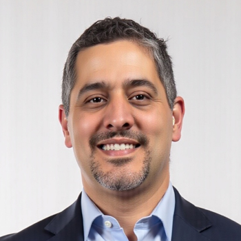 Headshot of a smiling man with a goatee in a suit.