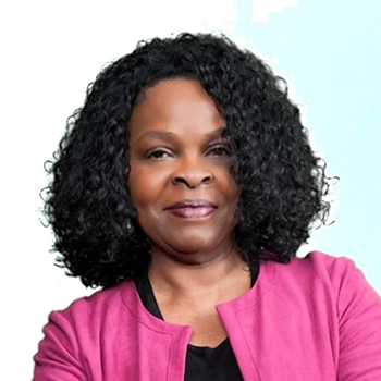 Headshot of a woman with curly black hair in a pink jacket.