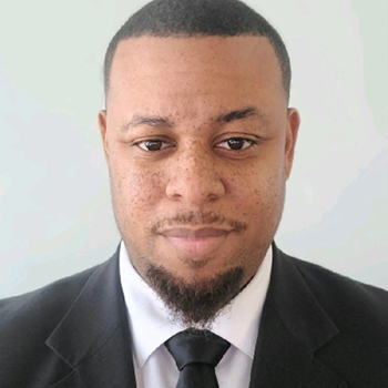 Headshot of a man in a suit jacket with black tie.